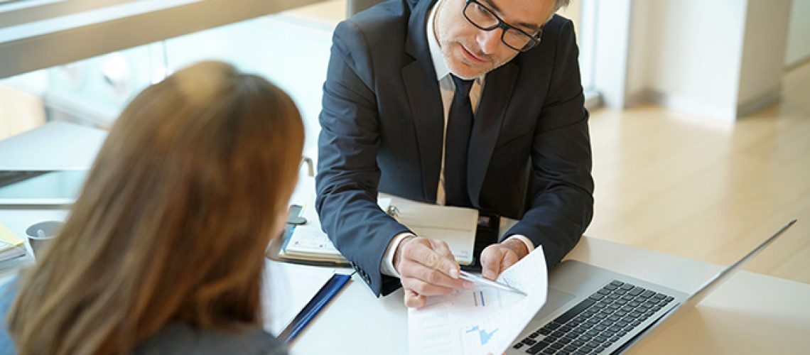 Woman in banker's office signing financial loan for project